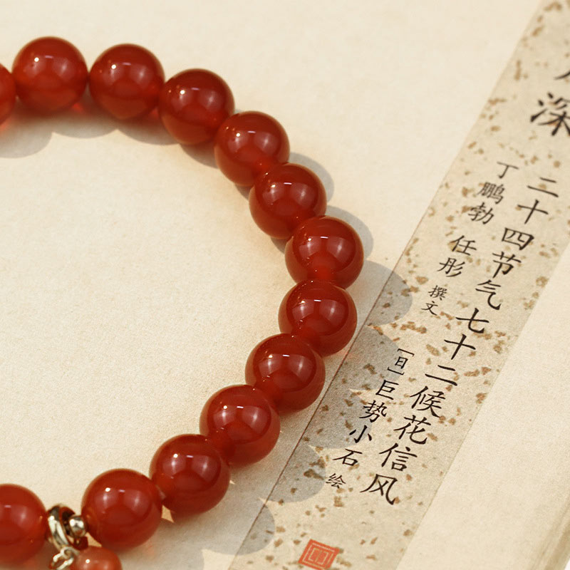 Red beaded bracelet on a textured beige background with Chinese text