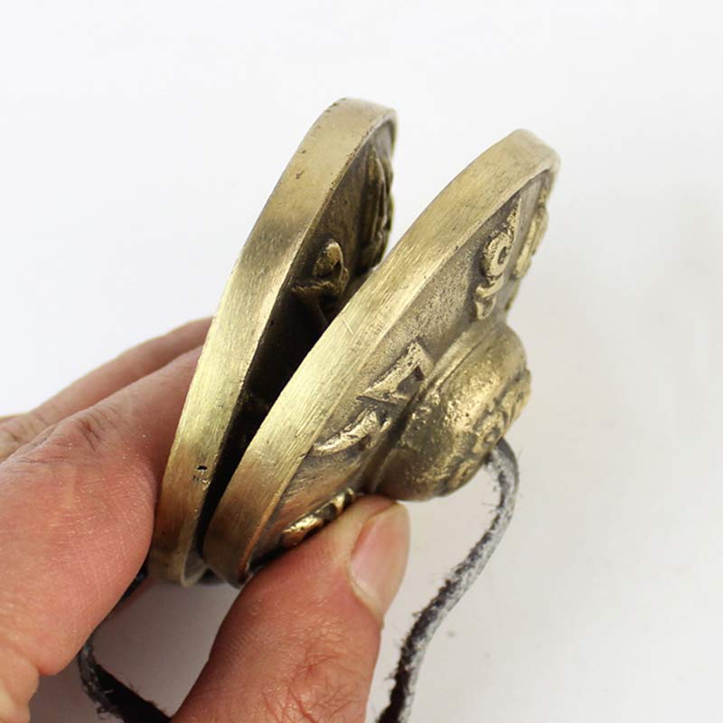 Hand holding a pair of brass handcuffs against a white background