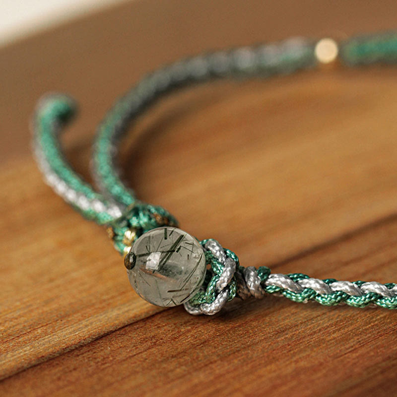 Green braided bracelet with a stone bead on a wooden surface
