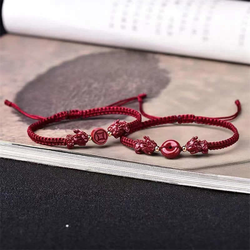 Red braided bracelet with decorative elements on a textured surface