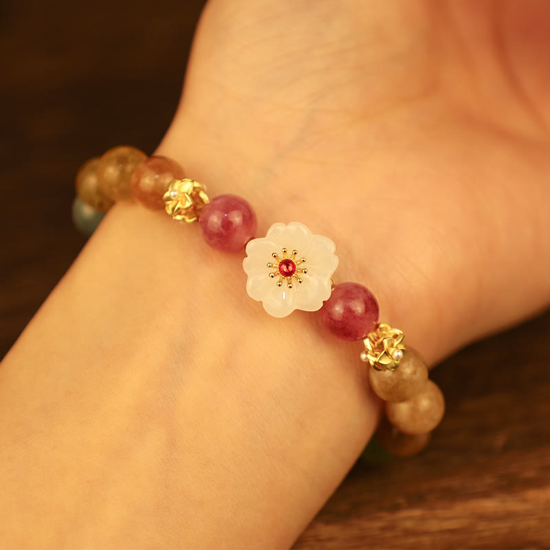 Bracelet with floral design and beads on a wrist against a warm-toned background