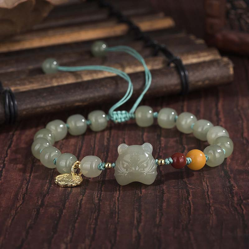 Beaded bracelet with a jade tiger charm on a wooden surface