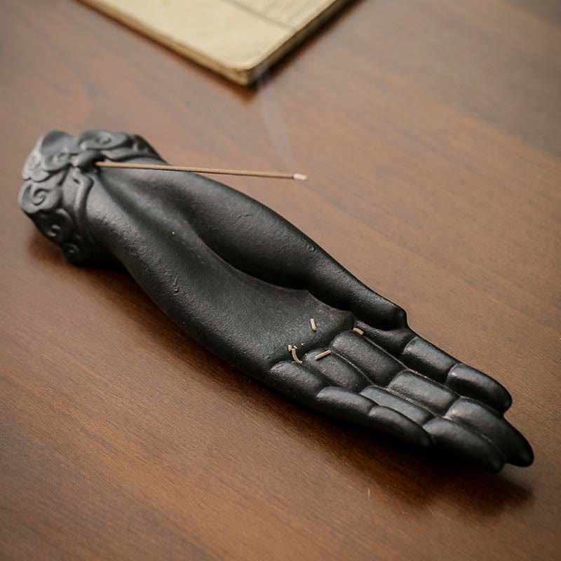 Black ceramic hand incense burner on a wooden surface