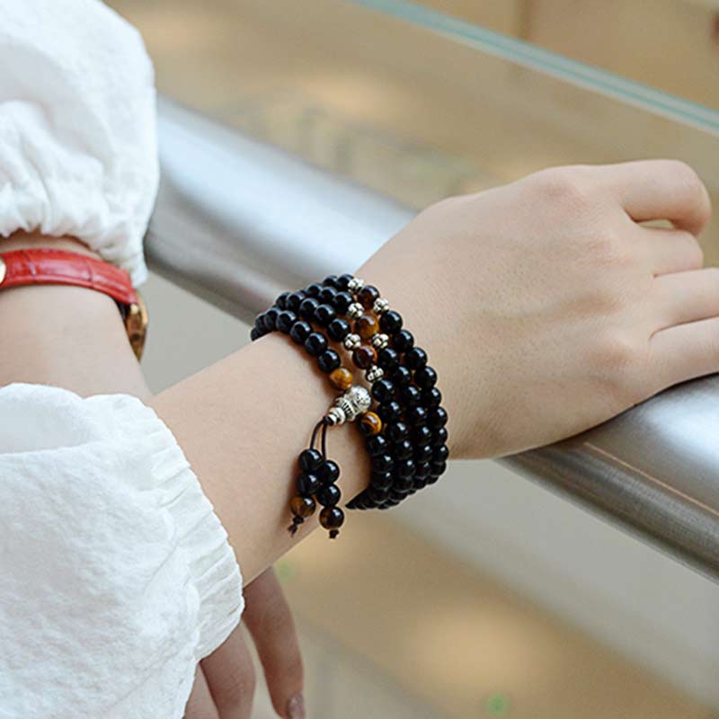 Person wearing a black beaded bracelet on a blurred background