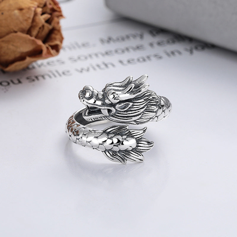Silver fish-shaped ring on a white surface with text