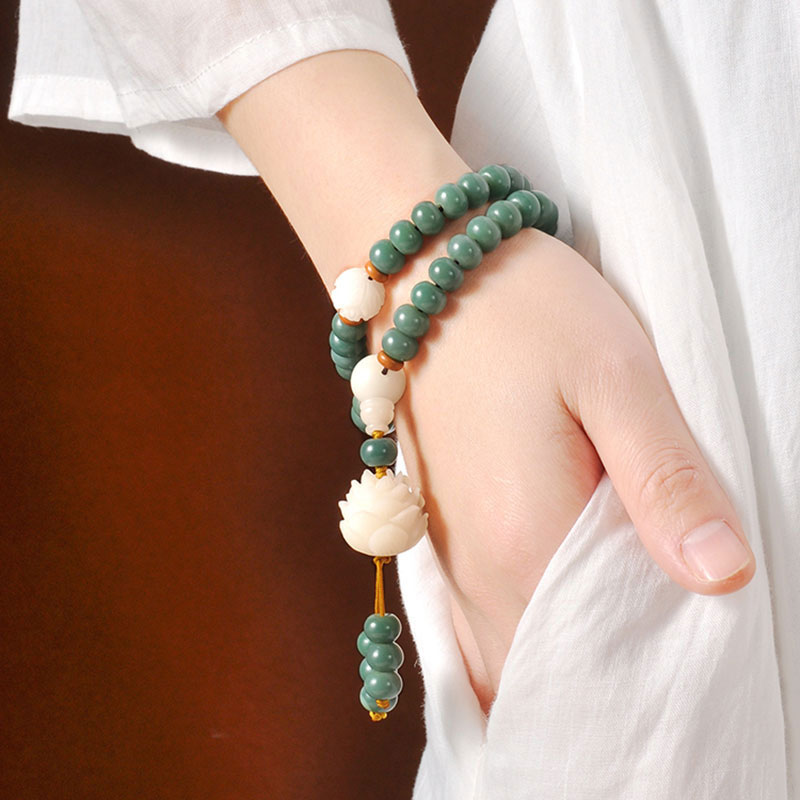 Close-up of a hand wearing a green beaded bracelet with a white background