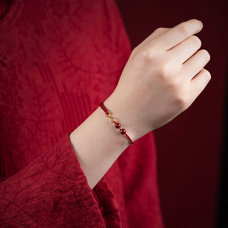 Hand wearing a red beaded bracelet against a red background