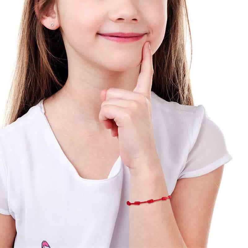 Close-up of a person wearing a white shirt with a red bracelet on a white background
