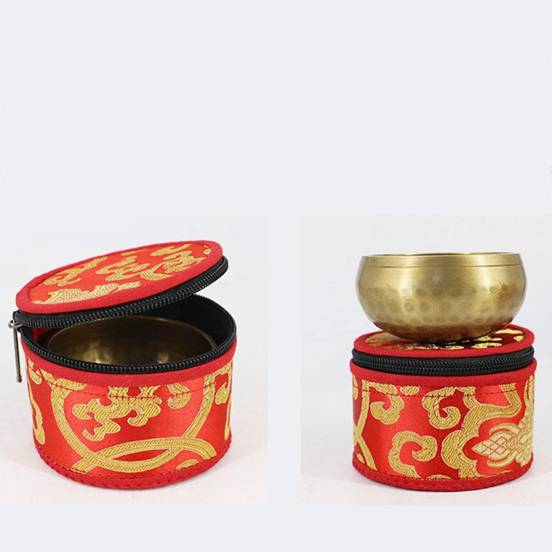Brass singing bowl with red and gold case on a white background