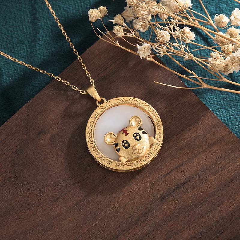 Gold necklace with a round pendant featuring a cartoon character on a wooden surface with dried flowers.