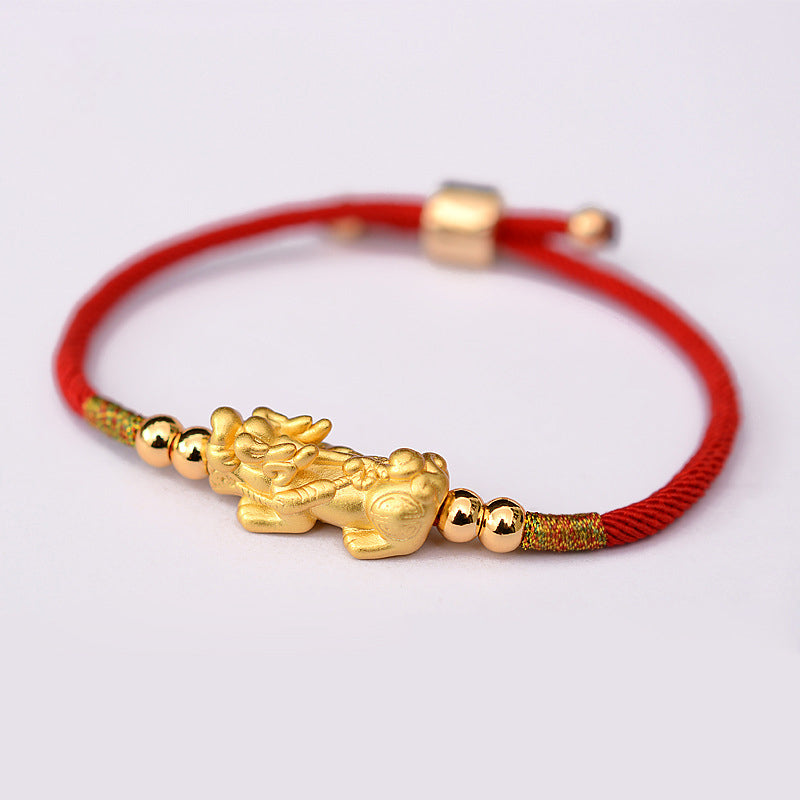 Red string bracelet with gold dragon charm on a white background