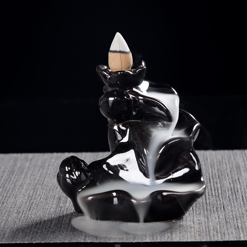 Black ceramic incense burner with white smoke on a dark background