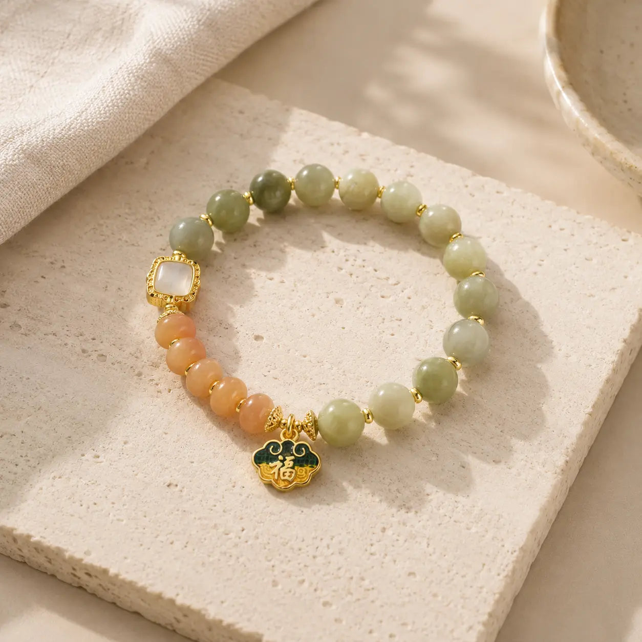 Golden Silk Jade Beaded Bracelet on light stone with gold charm