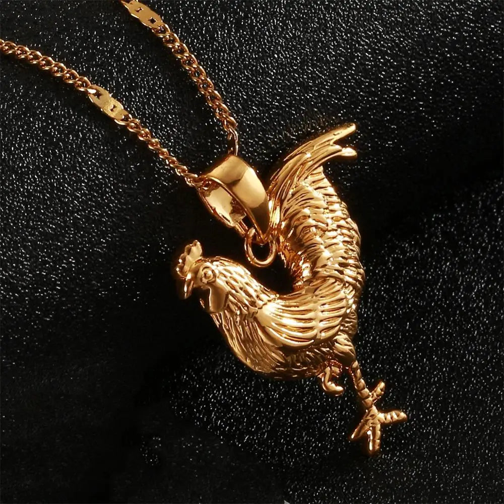 Gold rooster pendant on a chain against a black background
