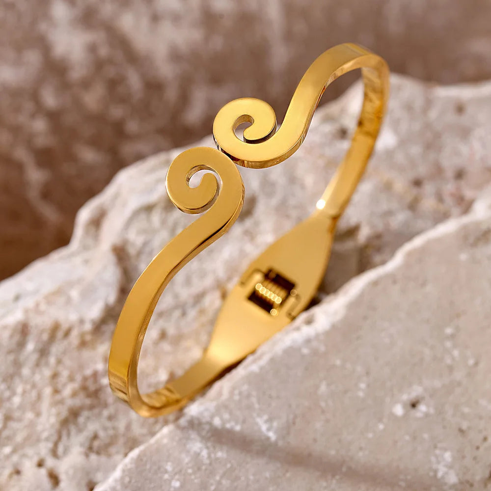 Gold bracelet with a decorative design on a textured stone surface