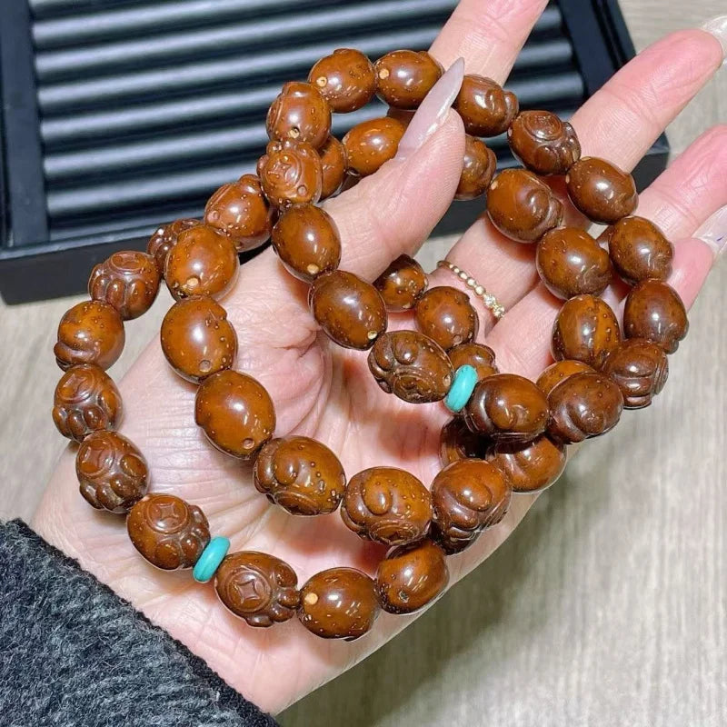 Brown beaded bracelet with turquoise accents on a hand against a neutral background