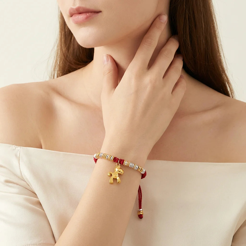 Woman wearing a gold and red bracelet on her wrist, with a neutral background