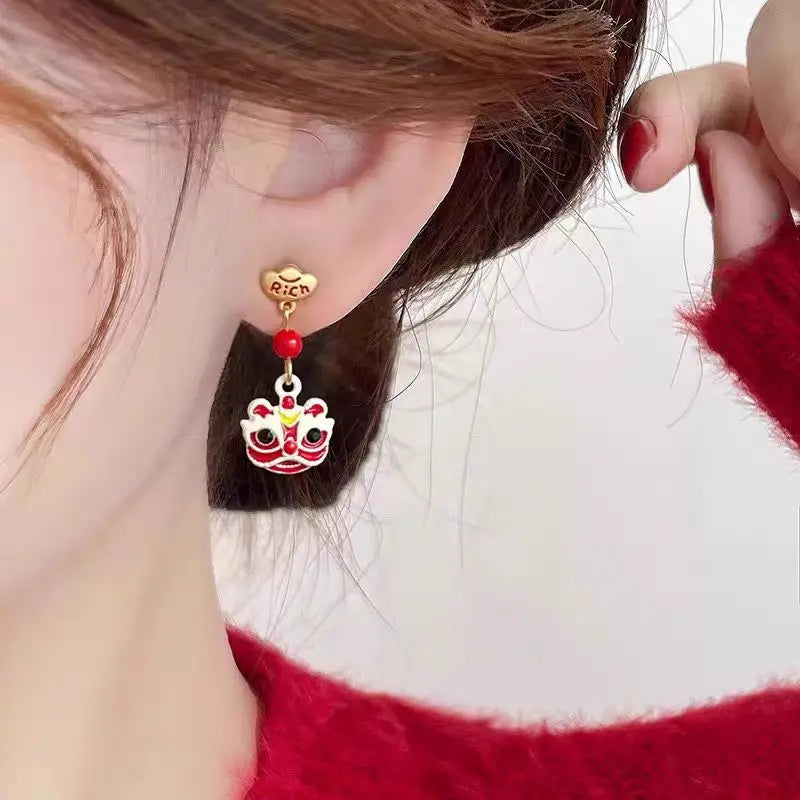 Close-up of a person wearing a decorative earring with a red and gold design.