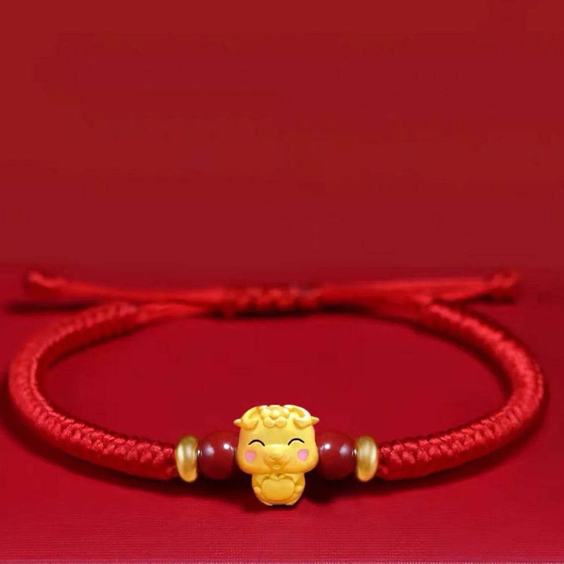 Red bracelet with a gold lion charm on a red background