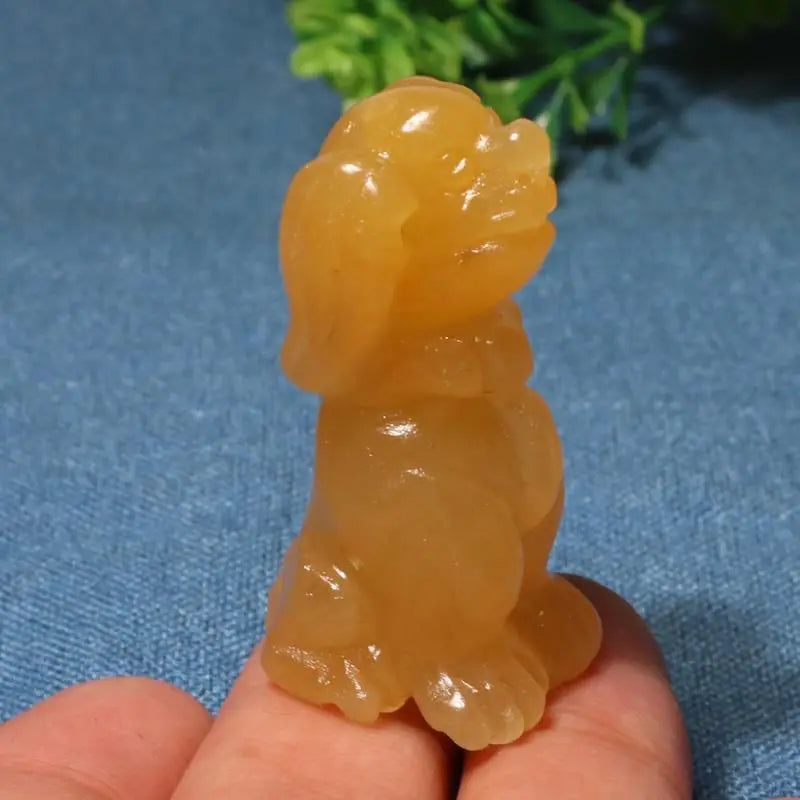 Translucent yellow stone sculpture of a dog held in a hand against a blue background