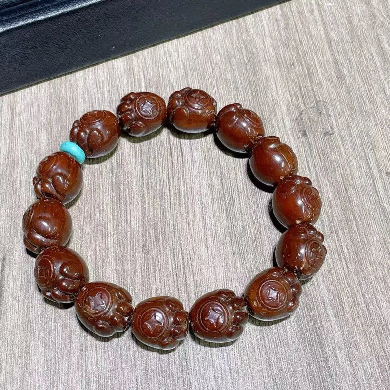 Brown beaded bracelet with a turquoise bead on a wooden surface