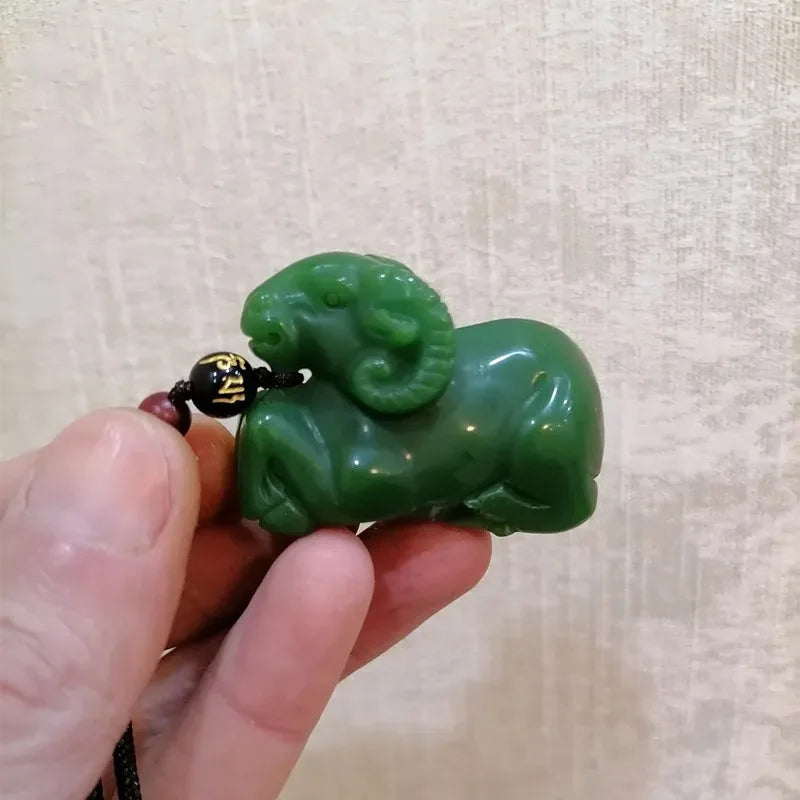 Green animal-shaped pendant held by a hand against a beige background