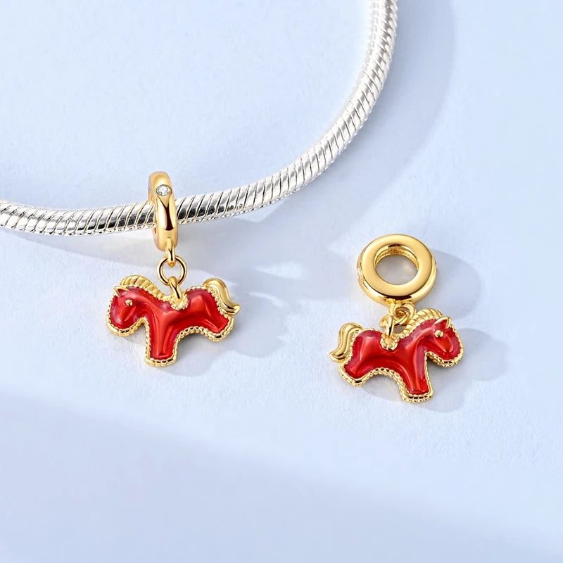 Two red horse-shaped charms on a silver snake chain against a light blue background