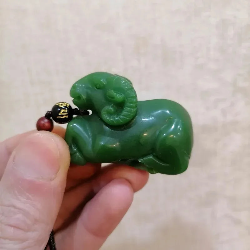 Green jade ram pendant held by a hand against a beige background