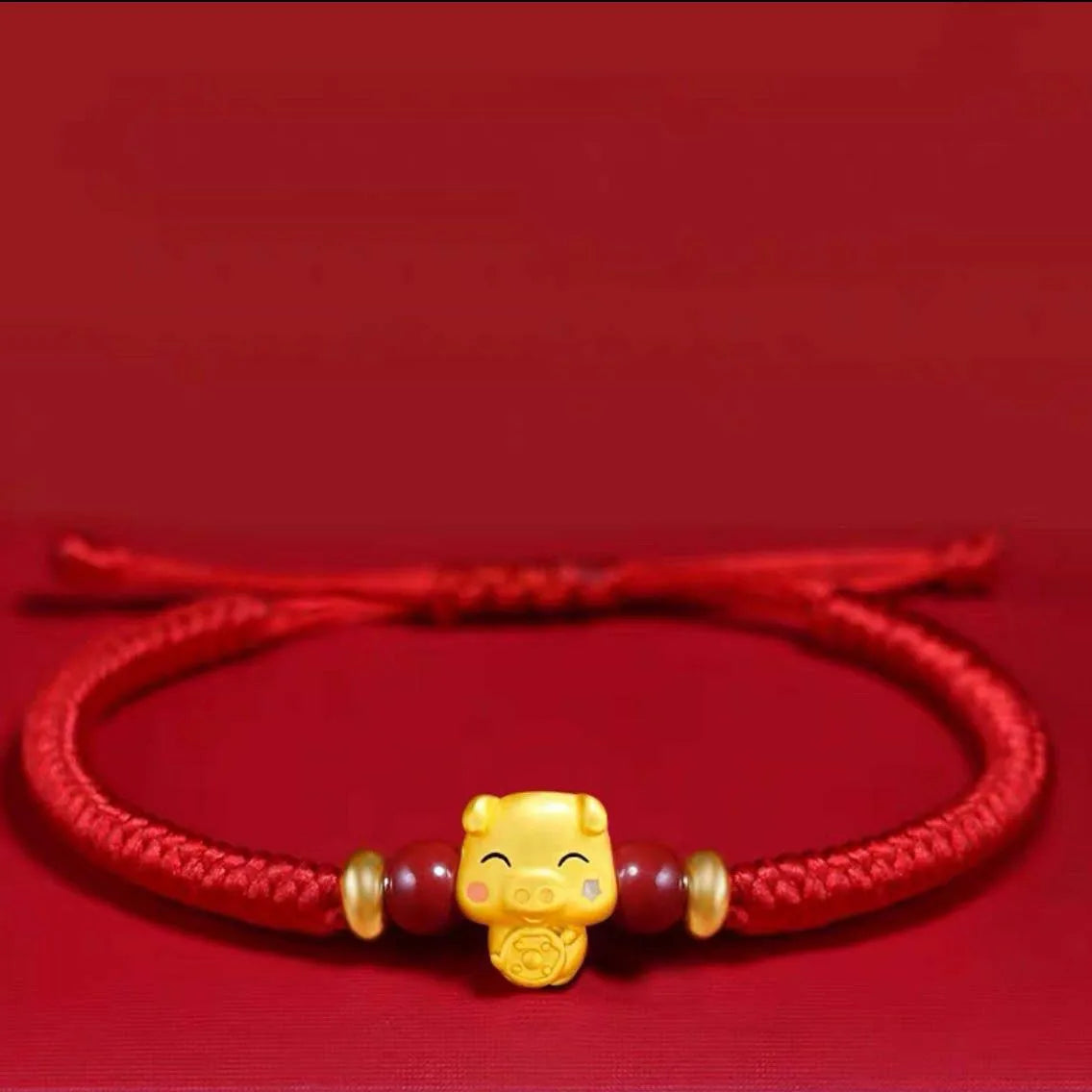 Red bracelet with a gold charm on a red background