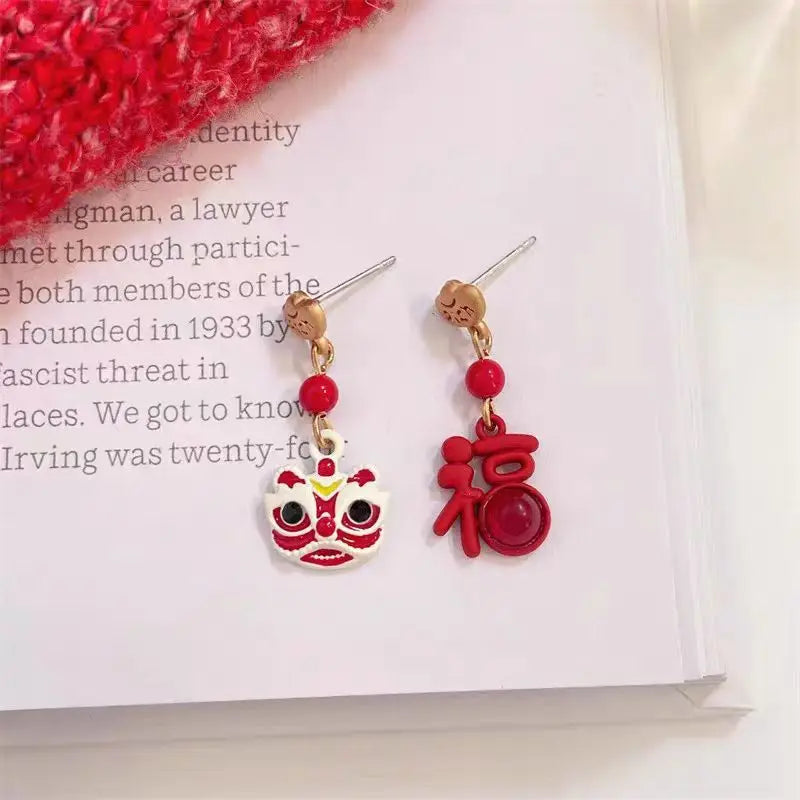 Red and gold earrings with a face design on a book page