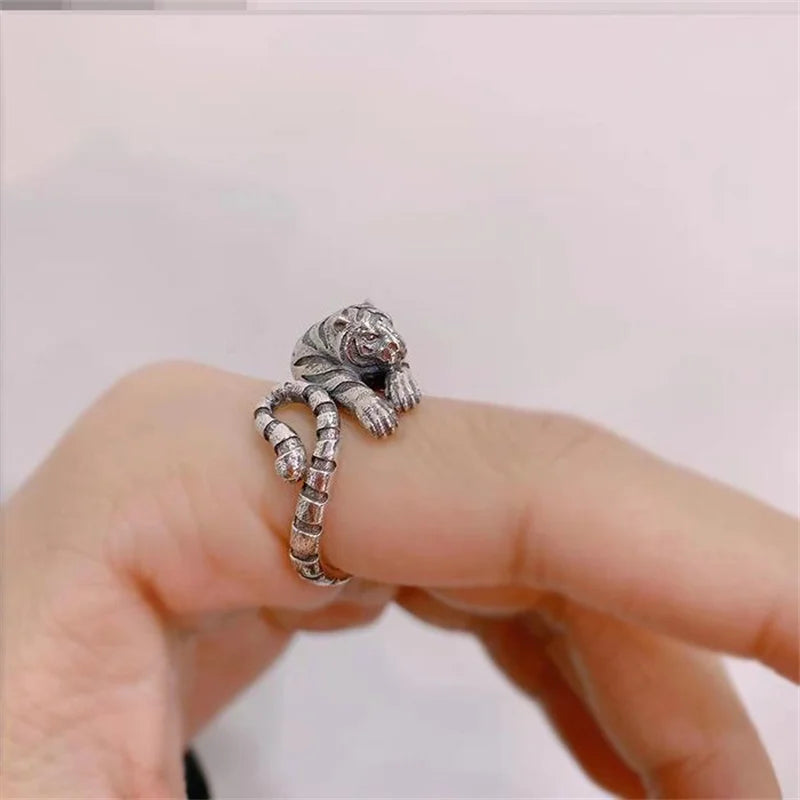 Silver ring with a lion head design on a finger against a white background