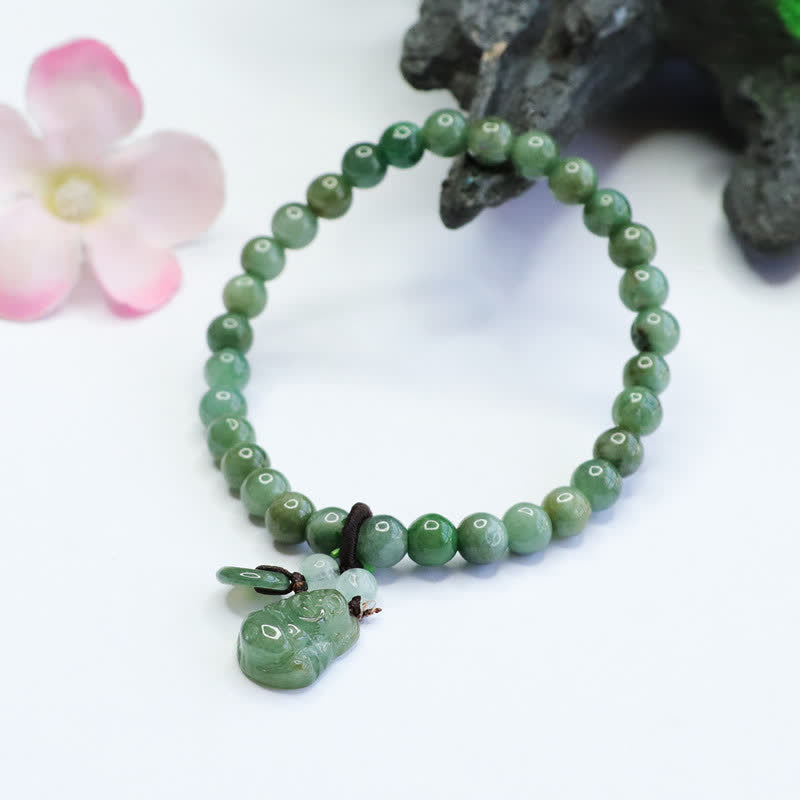 Green beaded bracelet with a small green charm on a white background