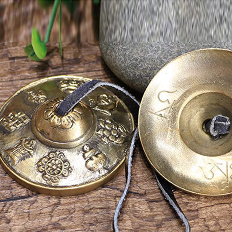 Two brass meditation chimes on a wooden surface with a blurred background