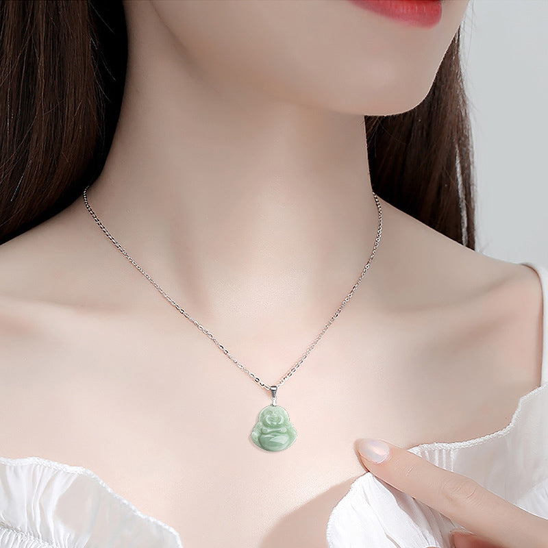 Woman wearing a necklace with a green pendant on a plain background