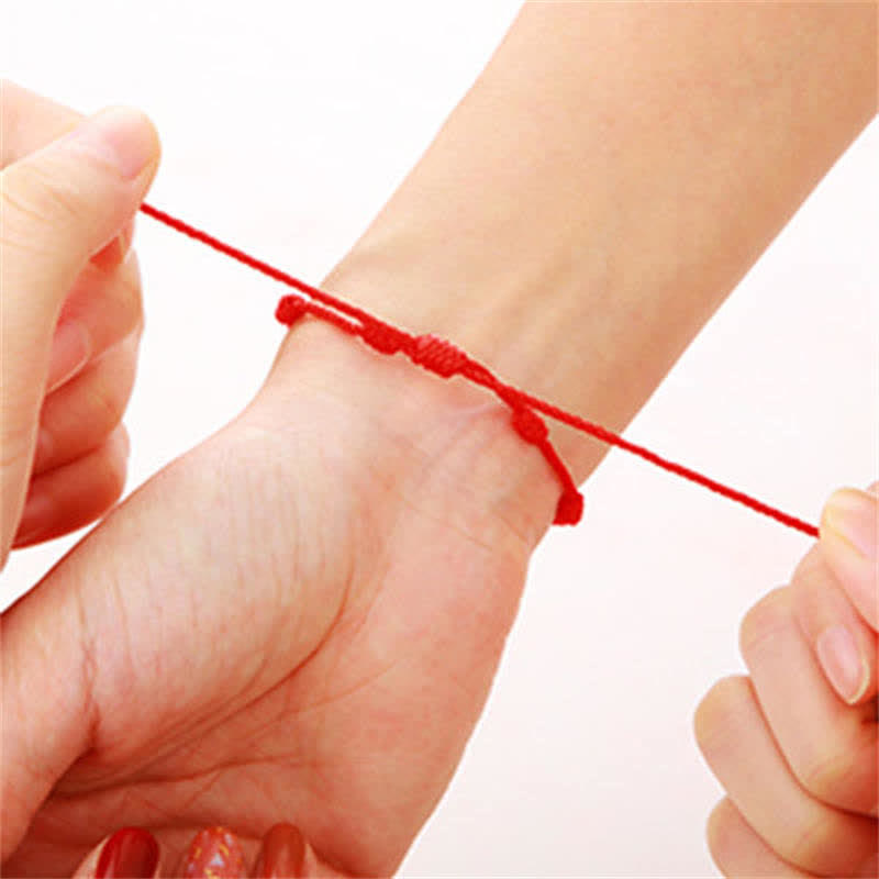 Person wearing a red string bracelet on a white background