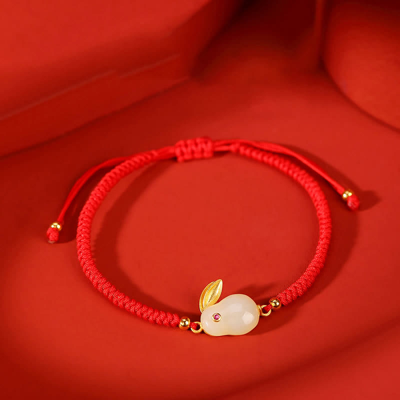 Red bracelet with a rabbit charm on a red background