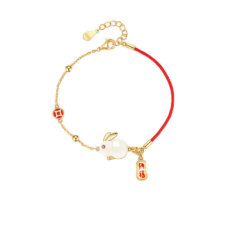 Bracelet with gold charm, red string, and rabbit pendant on a white background