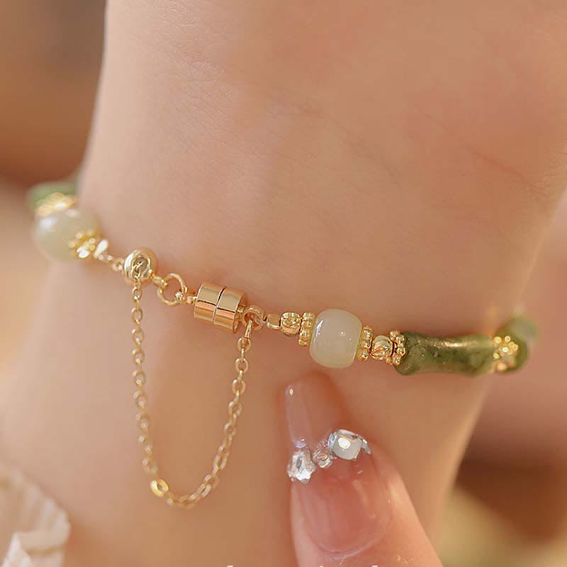 Gold bracelet with beads on a hand against a blurred background