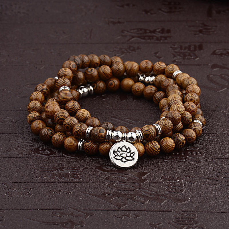Wooden beaded bracelet with silver lotus charm on a dark textured background