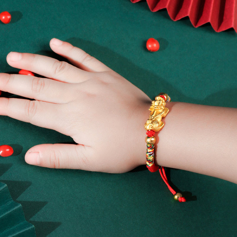 Hand wearing a gold and red bracelet on a green surface with red objects.