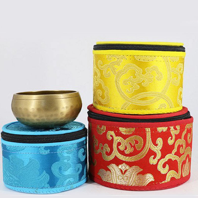 Three fabric-wrapped bowls in blue, yellow, and red with gold patterns on a white background.