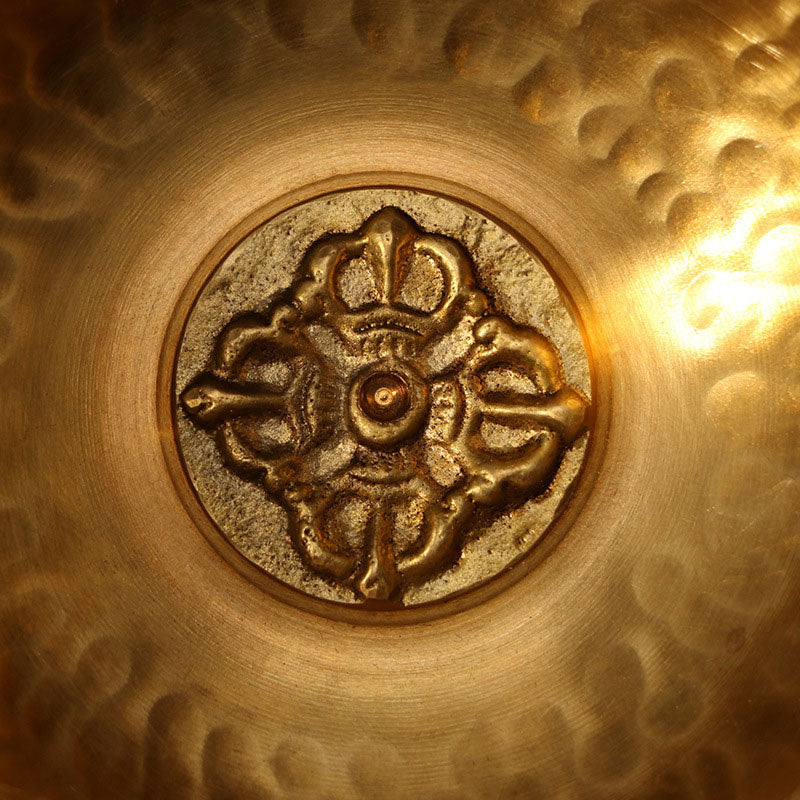 Close-up of a gold decorative emblem on a textured gold surface.
