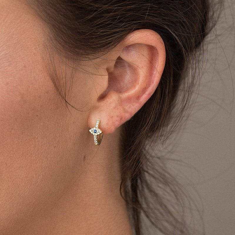 Close-up of an ear wearing a diamond earring with a neutral background