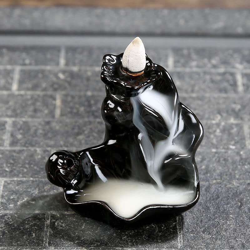 Backflow incense burner with smoke on a stone surface