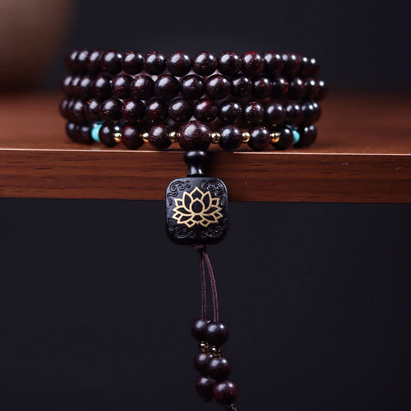Black beaded bracelet with a silver lotus flower charm on a wooden surface.