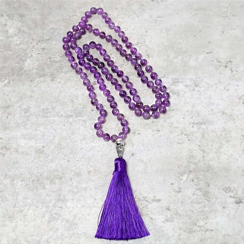 Purple beaded necklace with a tassel on a gray concrete surface