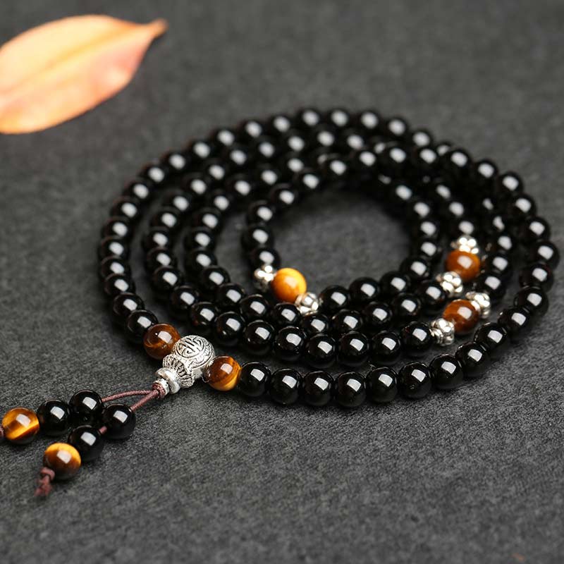 Black beaded necklace with brown and silver accents on a dark surface