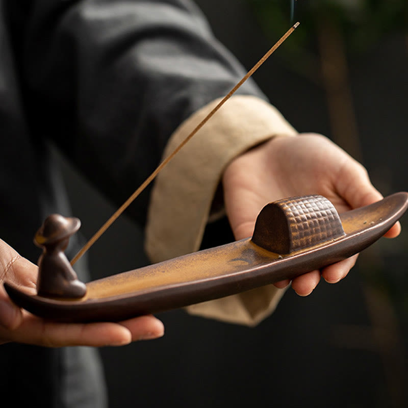 Person holding a wooden incense holder with incense sticks