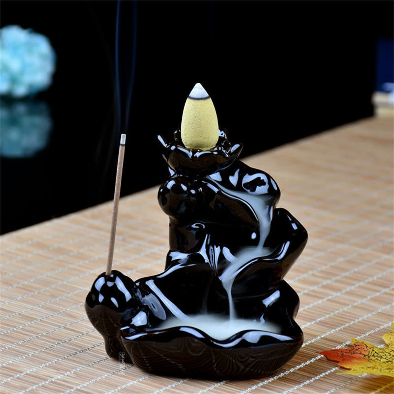 Black ceramic incense burner with a white incense cone on a woven surface.