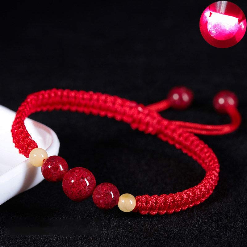 Red string bracelet with red and beige beads on a black background